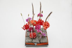 Selbstgemachtes Centerpiece für den Tisch mit Geranien als Schnittblumen, Strohhalmen und Pflastersteinen