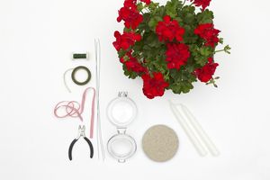 Materials for this DIY candleholder with geranium wreath are a jar, sand, candles, ribbon,a length of florist (stub) wire, reel wire, pliers and a red geranium.